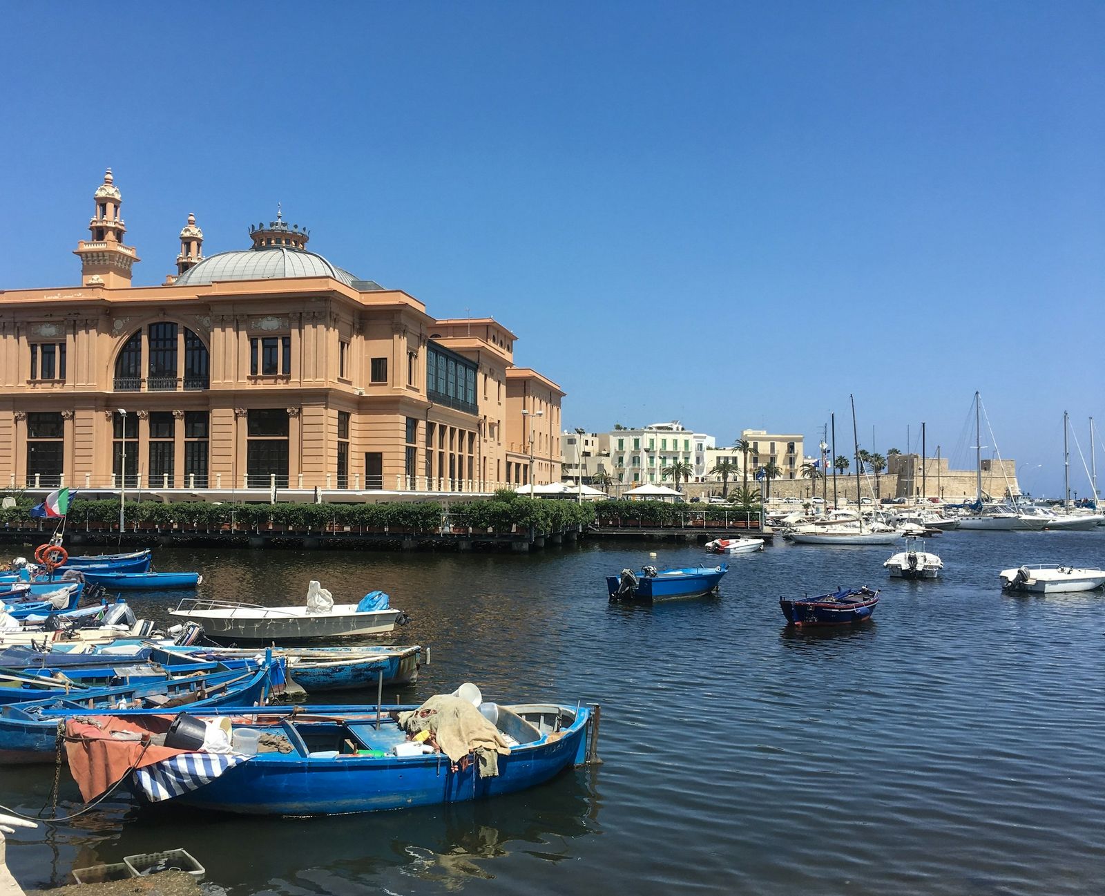 The Teatro Margherita across the old harbour, blue fishing boats moored in front